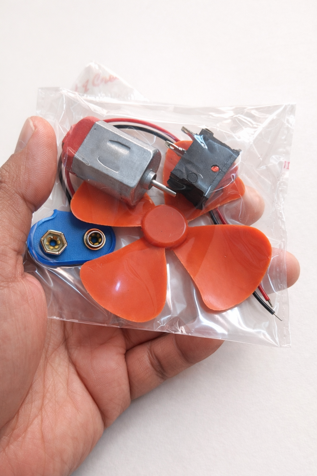 Small fan DIY kit with motor, battery connector, propeller, button and LED.